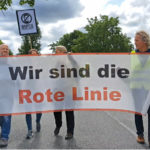 Drei Demonstranten tragen ein Banner mit der Aufschrift "Wir sind die rote Linie", dahinter ein Schild "Habeck absetzen"